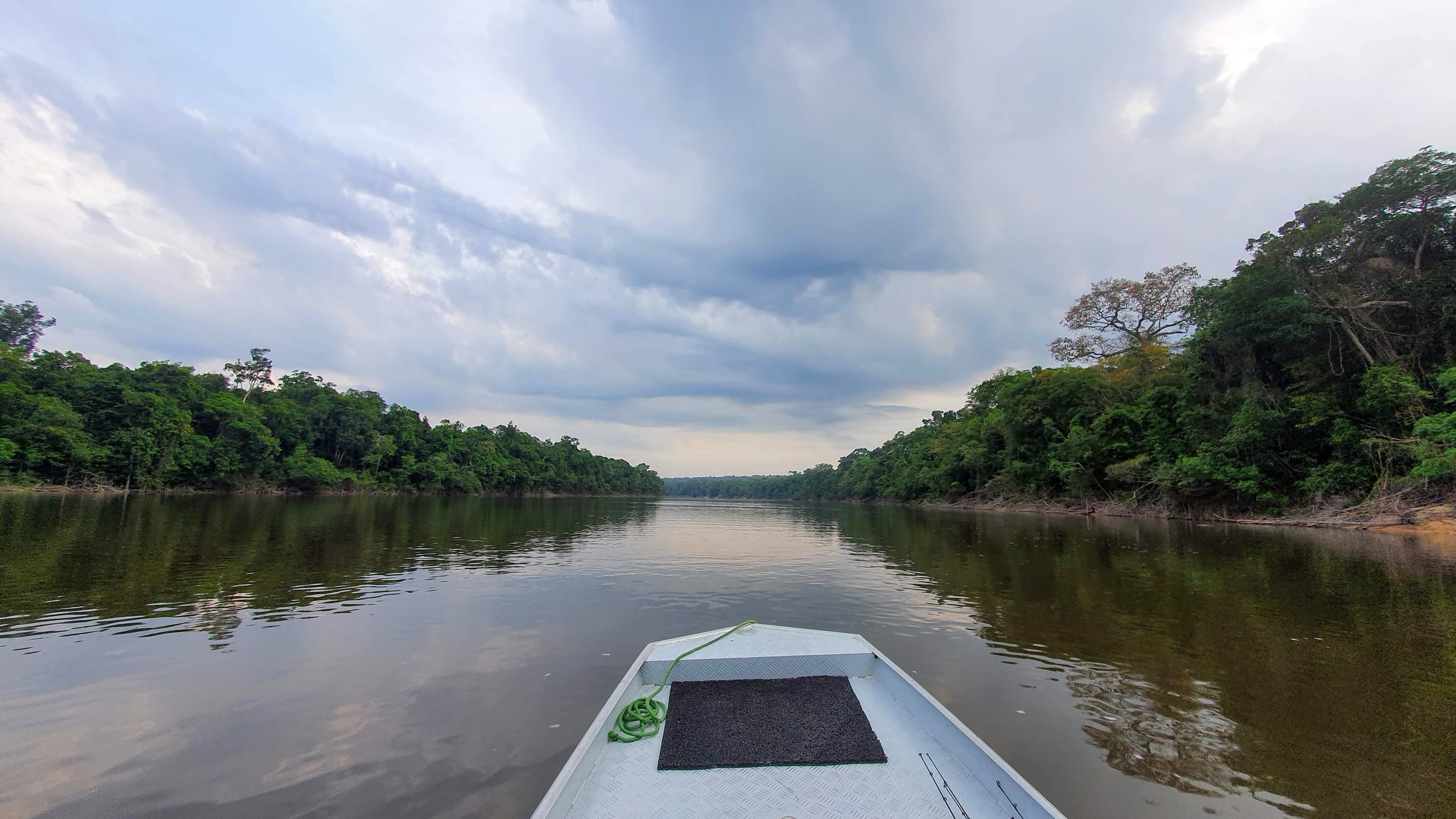 Barco descendo um rio amazônico ao amanhecer