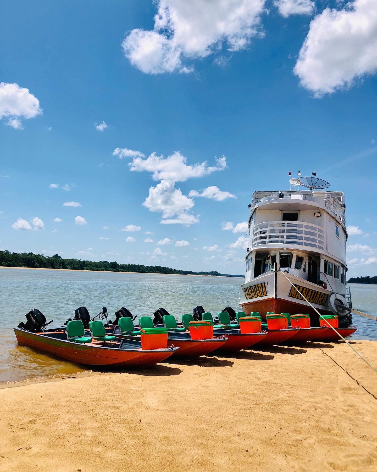 Barco-hotel Manauara ancorado em praia do Rio Branco com a frota de voadeiras