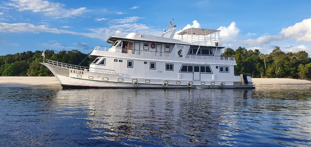 Barco-hotel Kalua I ancorado em praia fluvial do Rio Negro ao entardecer