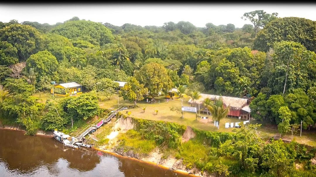 Vista aérea da pousada na margem do Rio Demeni com floresta amazônica ao redor