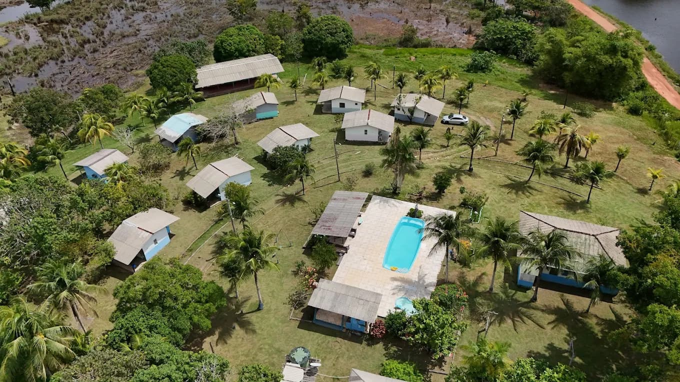 Vista aérea do complexo da Pousada Paraíso da Pesca Esportiva com chalés, piscina e lago ao fundo