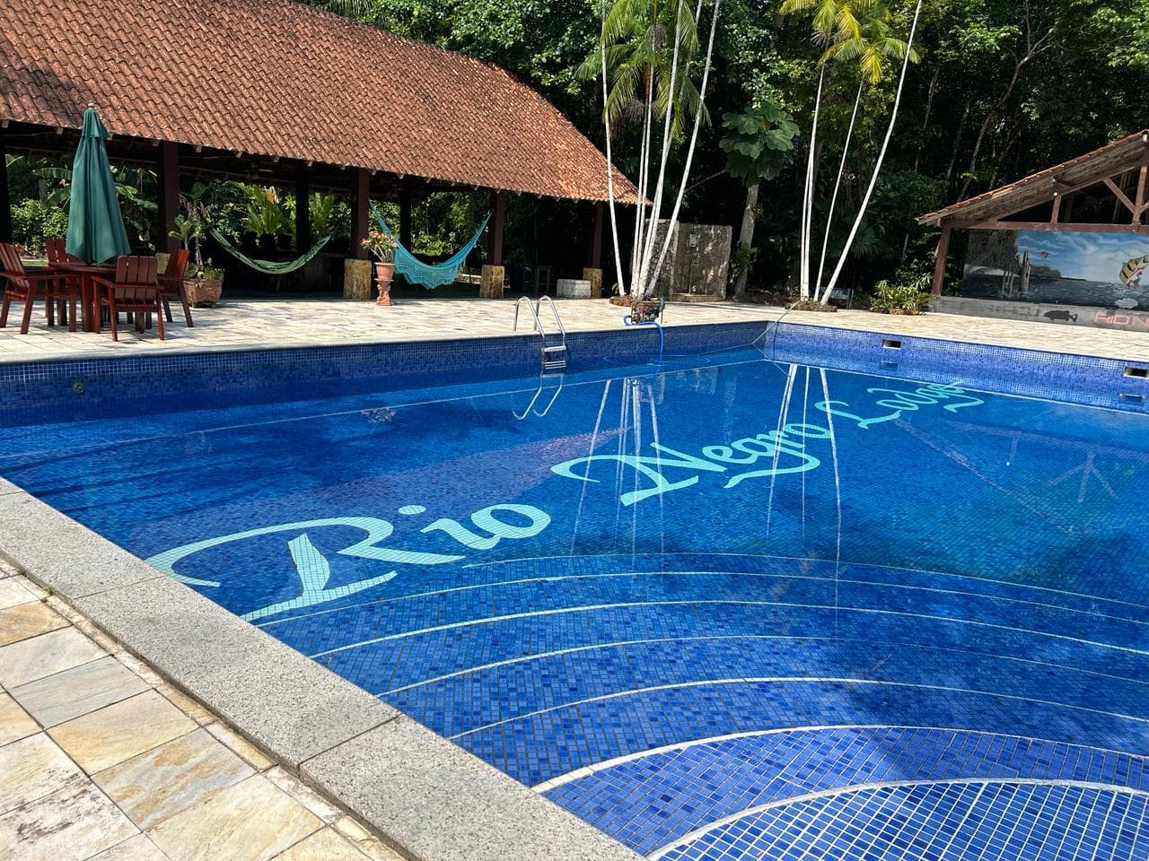 Piscina do Santana Rio Negro Lodge com mosaico Rio Negro Lodge no fundo e lounge coberto com redes